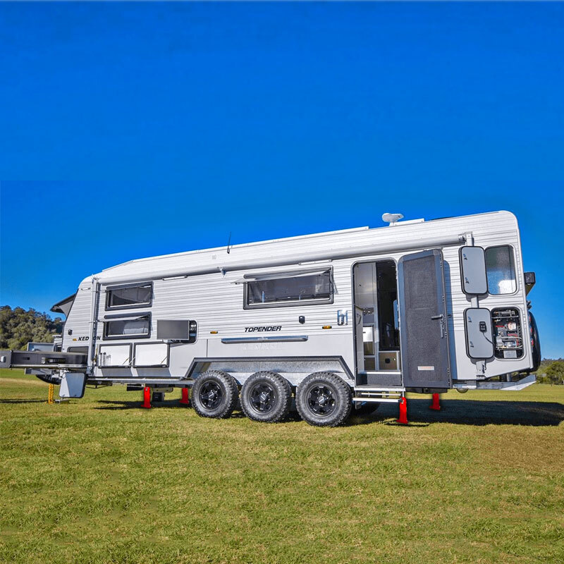 Redfoot Levelling - A white RV parked on a grassy field utilizing Redfoot Hydraulic 'Levelling' for Caravans.