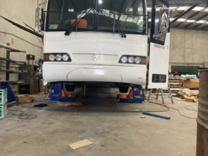 Redfoot Levelling - A white bus is being worked on in a garage.