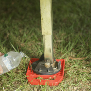 Redfoot Levelling - A person pouring water into a bottle using Redfoot Levelling 'Anti Ant' Stabiliser Pads.