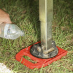 Redfoot Levelling - A person using Redfoot Levelling 'Anti Ant' Stabiliser Pads for a crane to pour water into a bottle on the ground.
