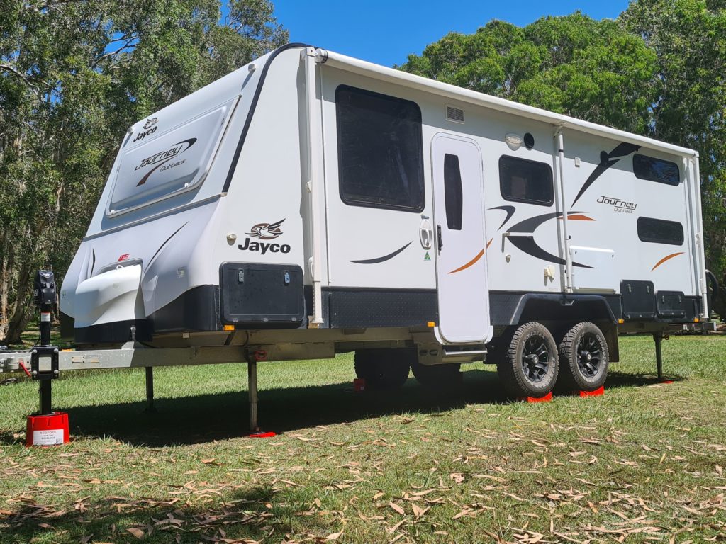 Redfoot Levelling - A black and white motorhome parked on grass with Redfoot Levelling Camper Levellers.