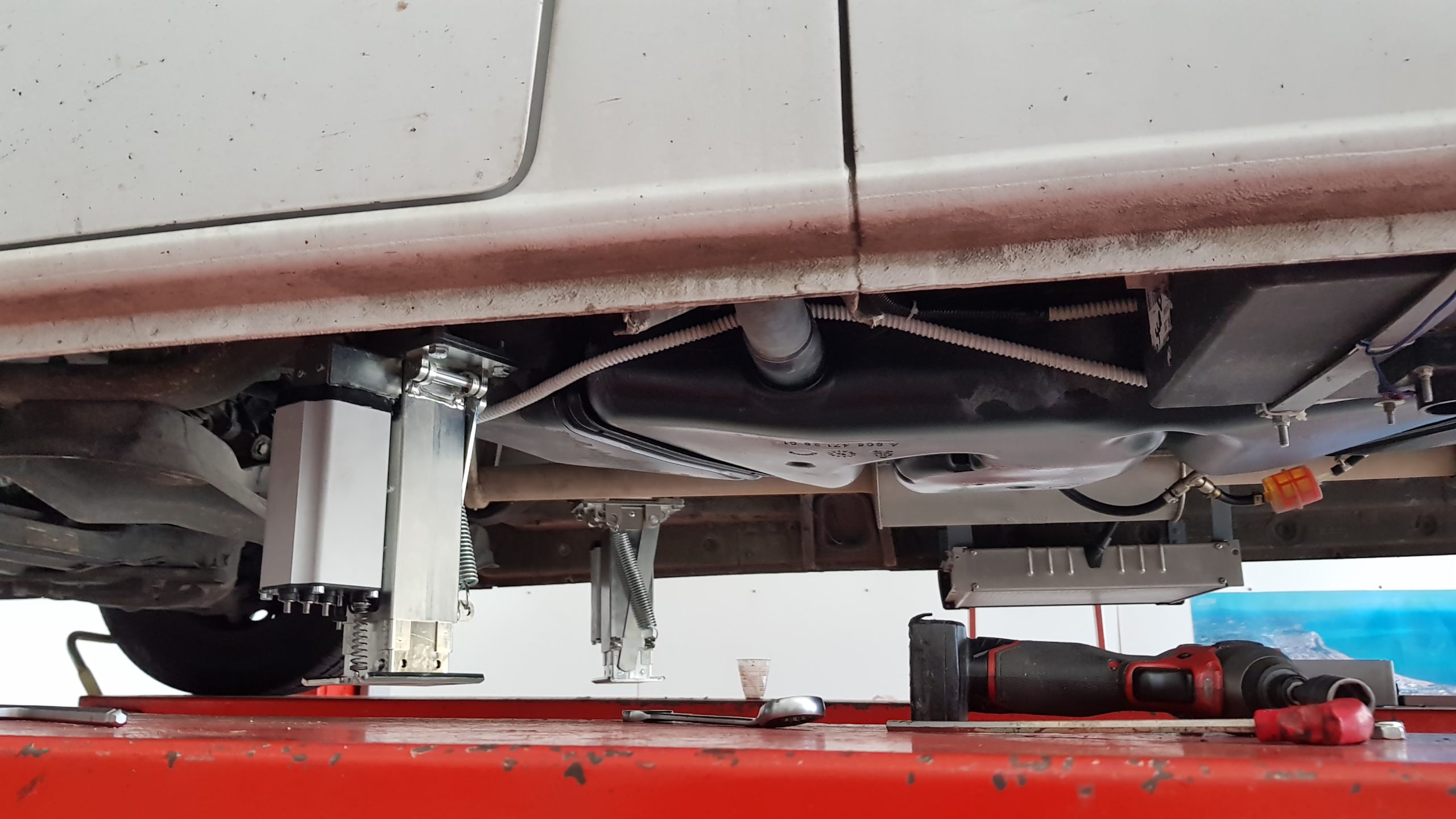 Redfoot Levelling - The underside of a car with a tire under it and the Redfoot Levelling Mercedes Benz 'AutoLift' system.