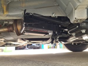 Redfoot Levelling - The underside of a Fiat car with an exhaust pipe and Redfoot Levelling Fiat ‘AutoLift’ System.